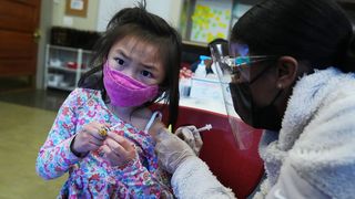 A young girl in a pink mask has been vaccinated.